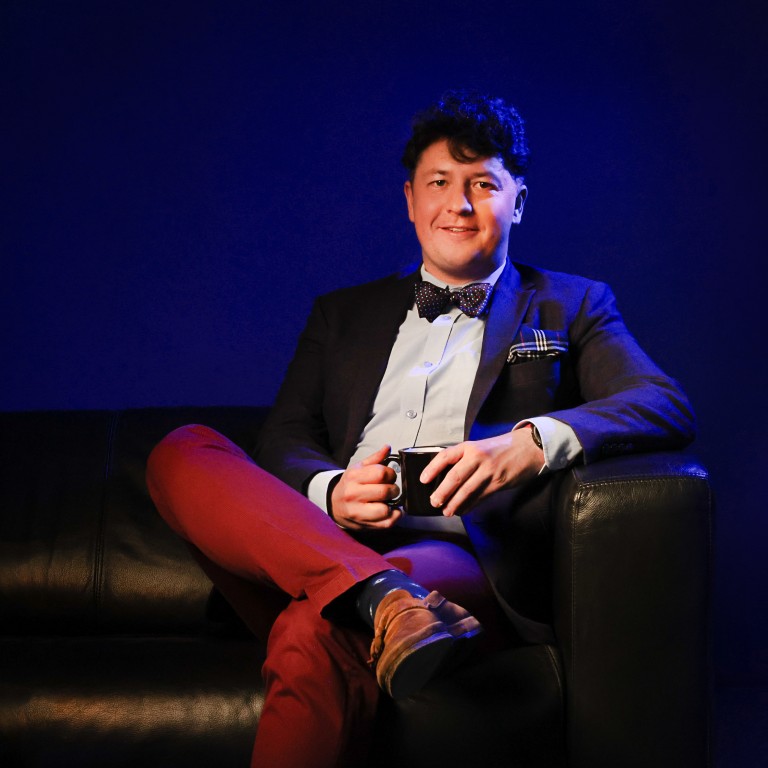 Michał Siejda siedzi na kanapie i w ręce trzyma kubek